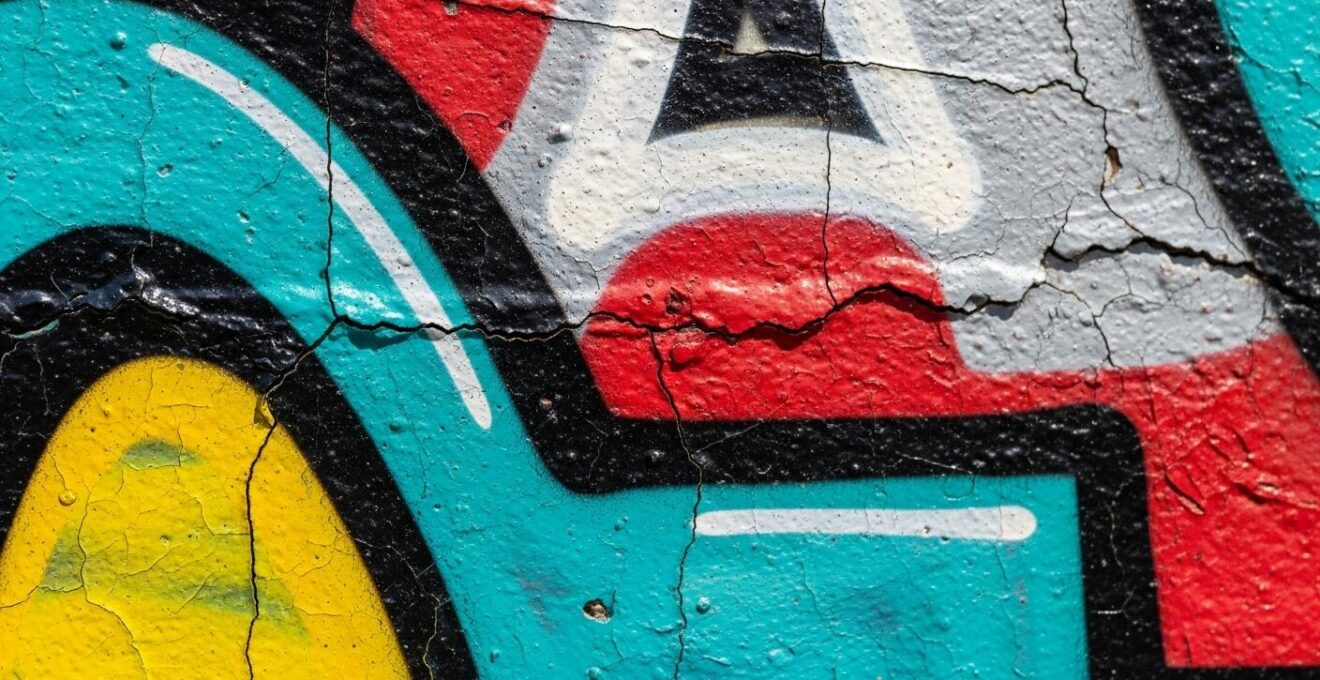 Photographie macro montrant des détails de textures et couleurs variées caractérisant un tag, un graffiti et une murale